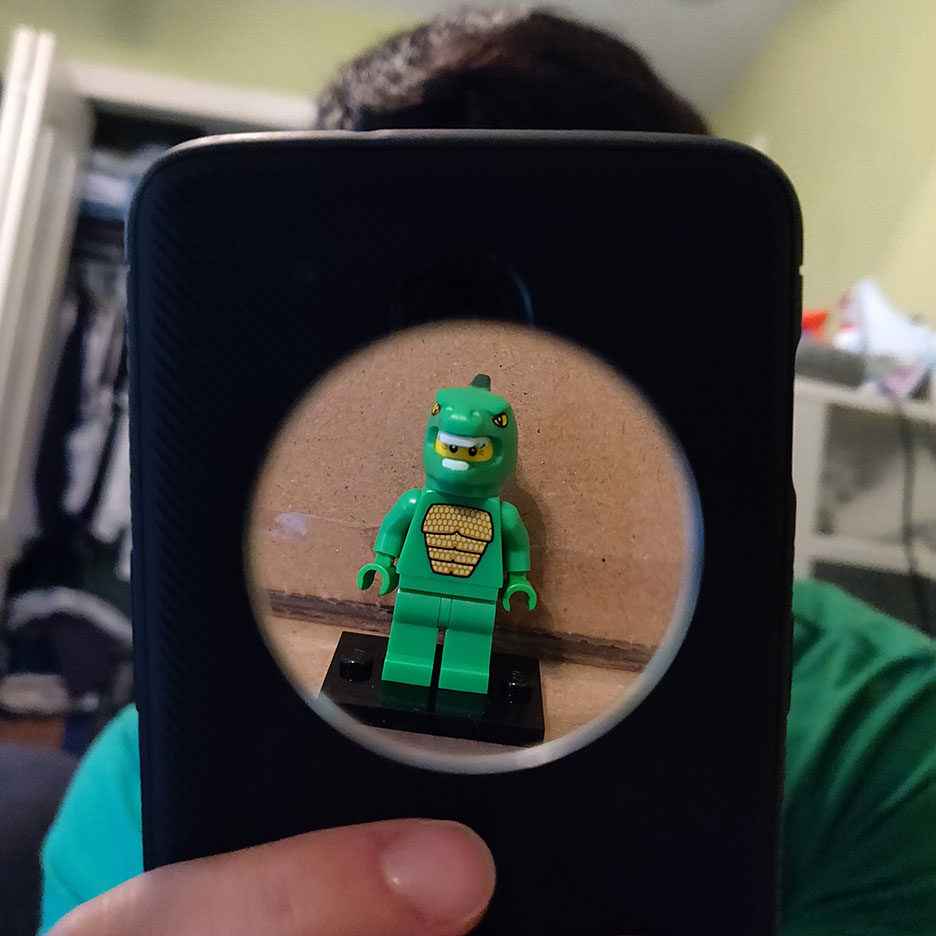 photo of a man taking a selfie. the mans face is covered by a LEGO dinosaur figurine.